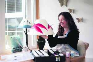 Olive Murphy of Olive Murphy Designs, working in her studio, handpainting a fuchsia lampshade.